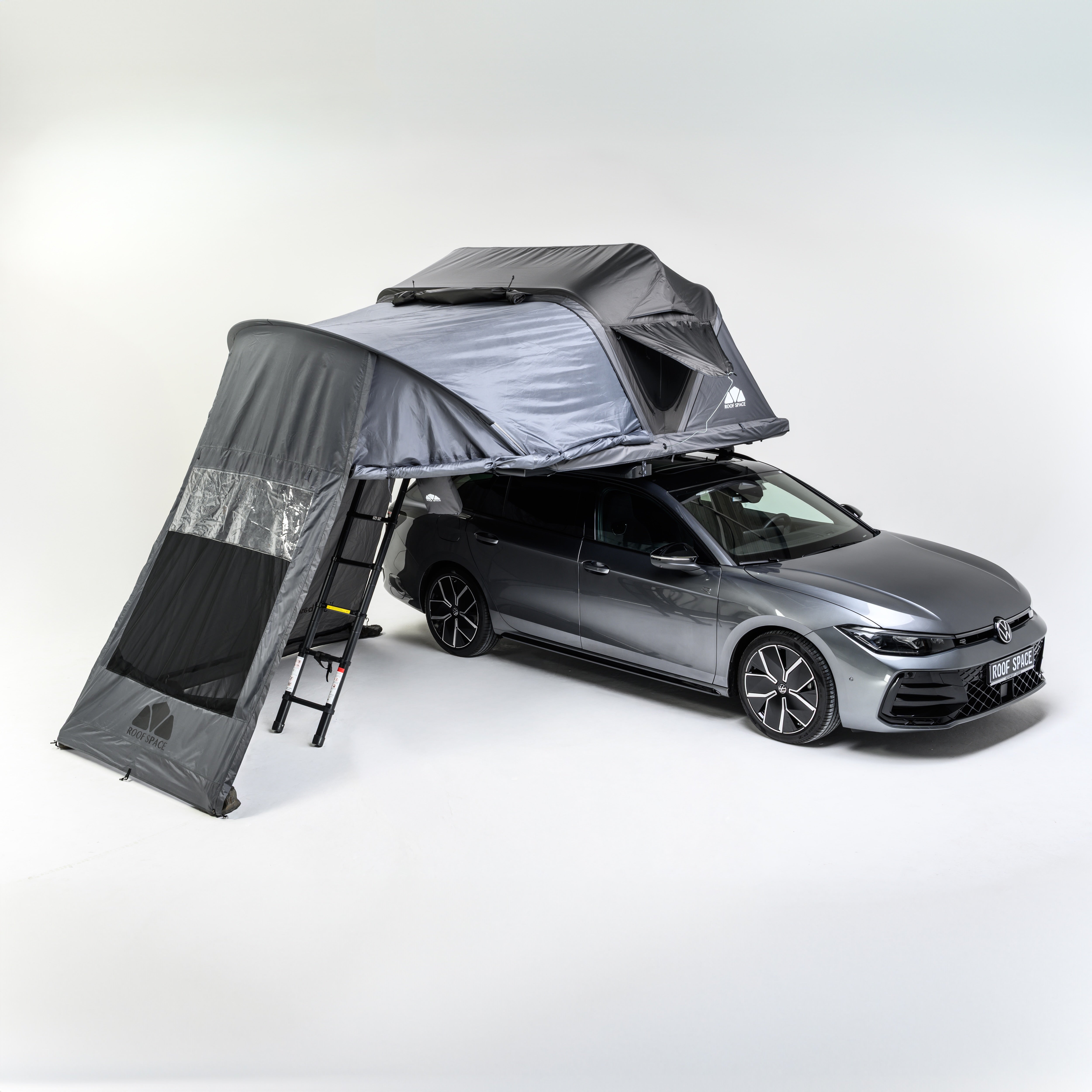 Ein grauer VW Golf mit einem montierten, grauen Dachzelt mit Leiter auf weißem Hintergrund. Auf dem Nummernschild steht "Roof Space".