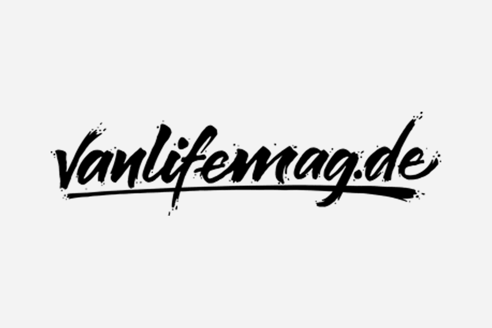 Schwarze, kalligrafische Schrift "Vanlifemag.de" auf weißem Hintergrund, mit einer dekorativen Unterstreichung.